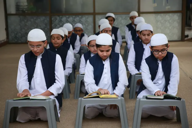 Students in Noon Islamic Academy uniform reading the Quran on low desks in a classroom