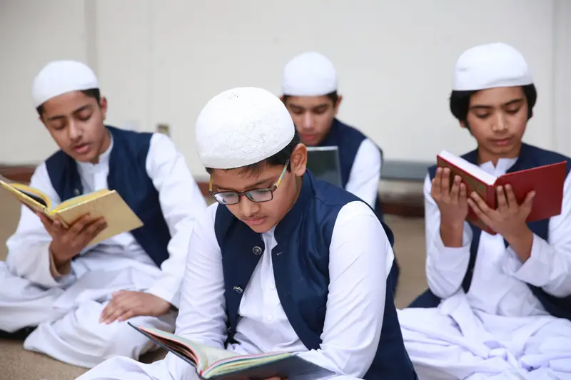 Four students in academy uniform reading from the Quran together