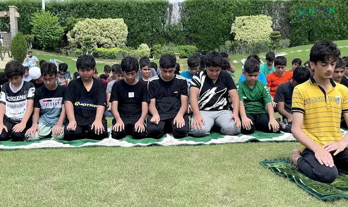 Students praying in rows on the grass outdoors
