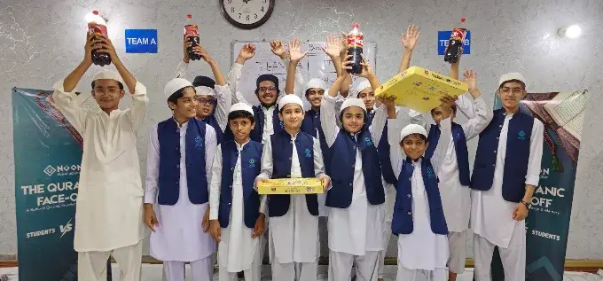 Students in academy uniform cheering at The Quranic Face-Off event, holding up prizes