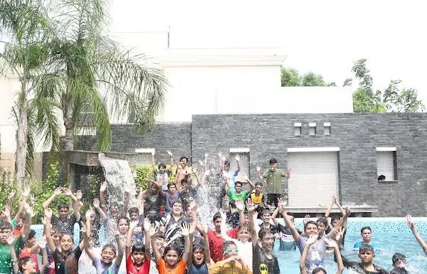 A large group of children cheering in a swimming pool during a summer trip